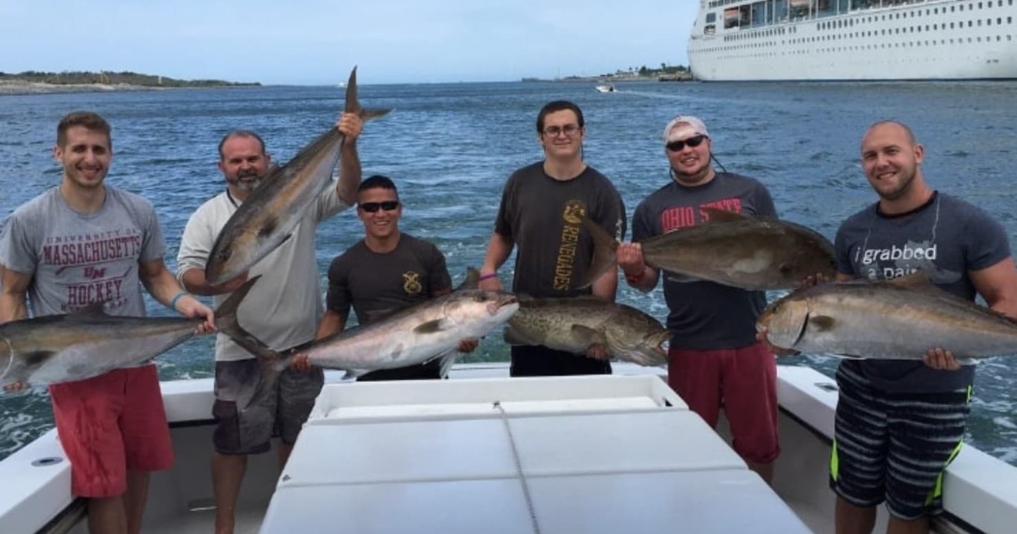 Group deep-sea fishing with multiple catch alongside harbor and cruise ship