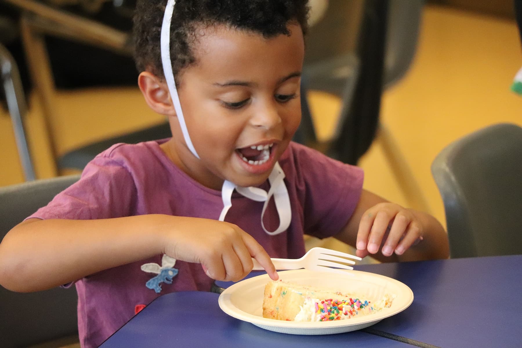 Child enjoying birthday cake indoors at a playful learning event
