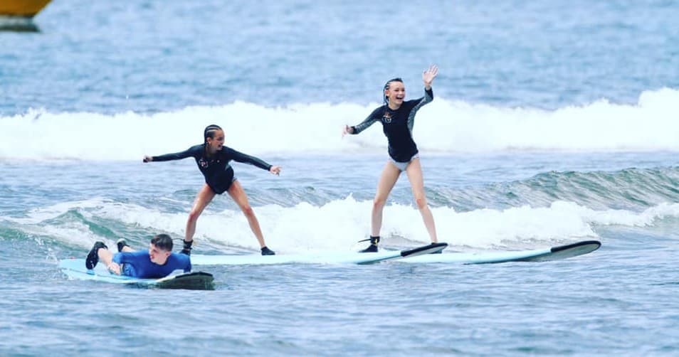Two surfers practicing standing on foam boards in small waves