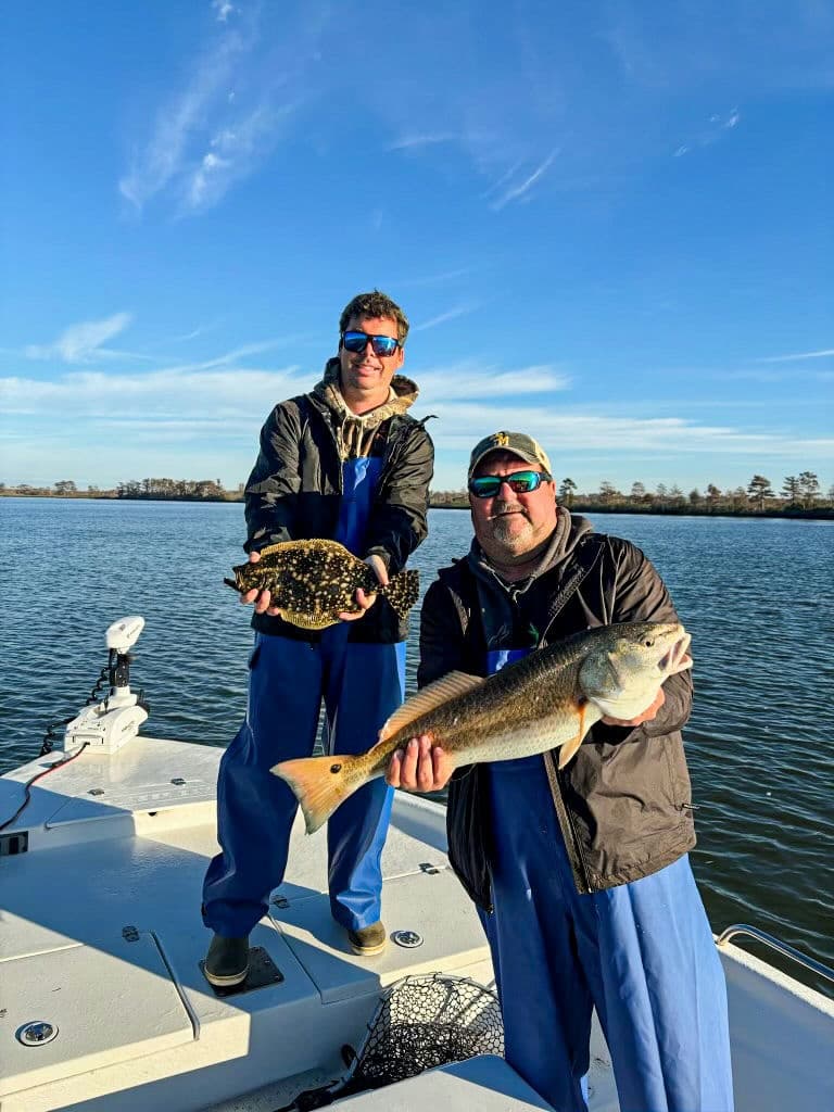 Two anglers displaying catch on bow of boat in coastal flats