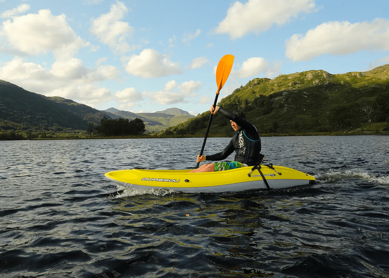 Solo kayaker paddling on Loch Lomond with hills
