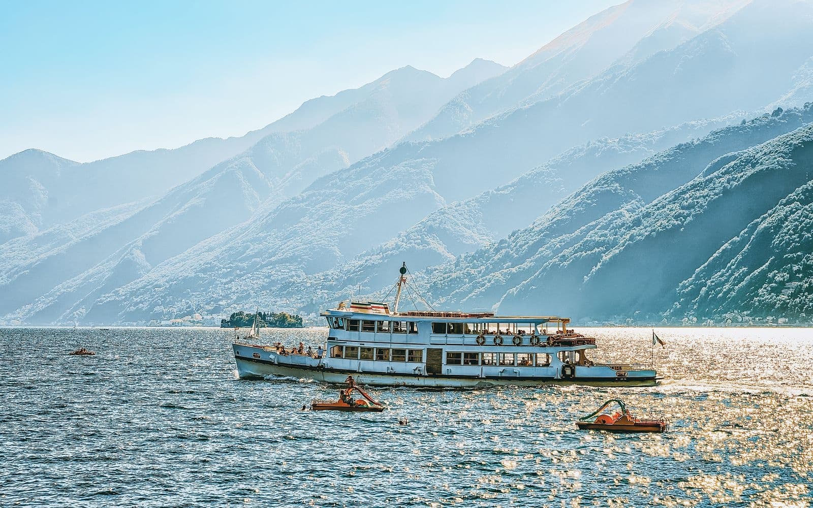 Scenic boat cruise on mountain lake with paddle boats