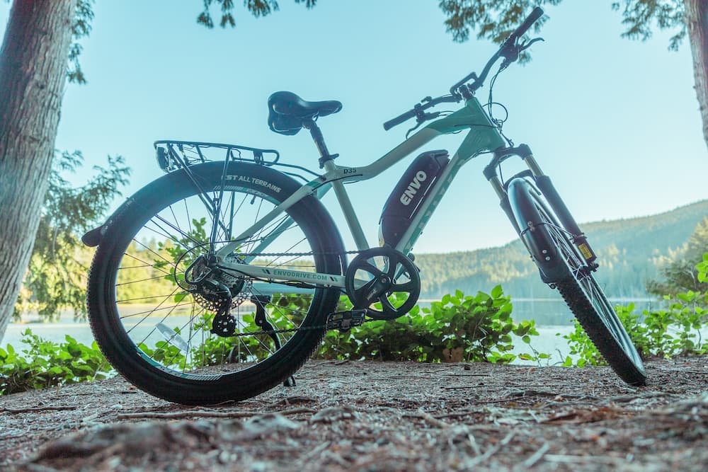 Electric bike leaning lakeside under trees, scenic ride