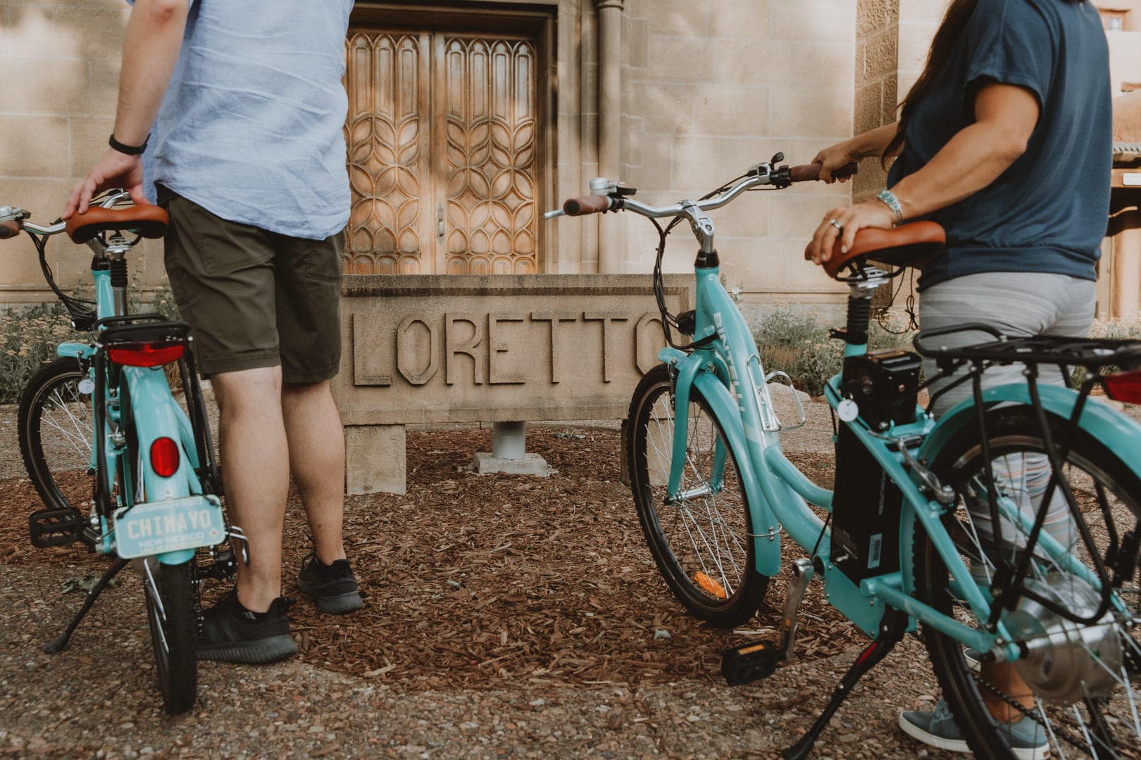 Two people preparing bicycles outside in sunny village street