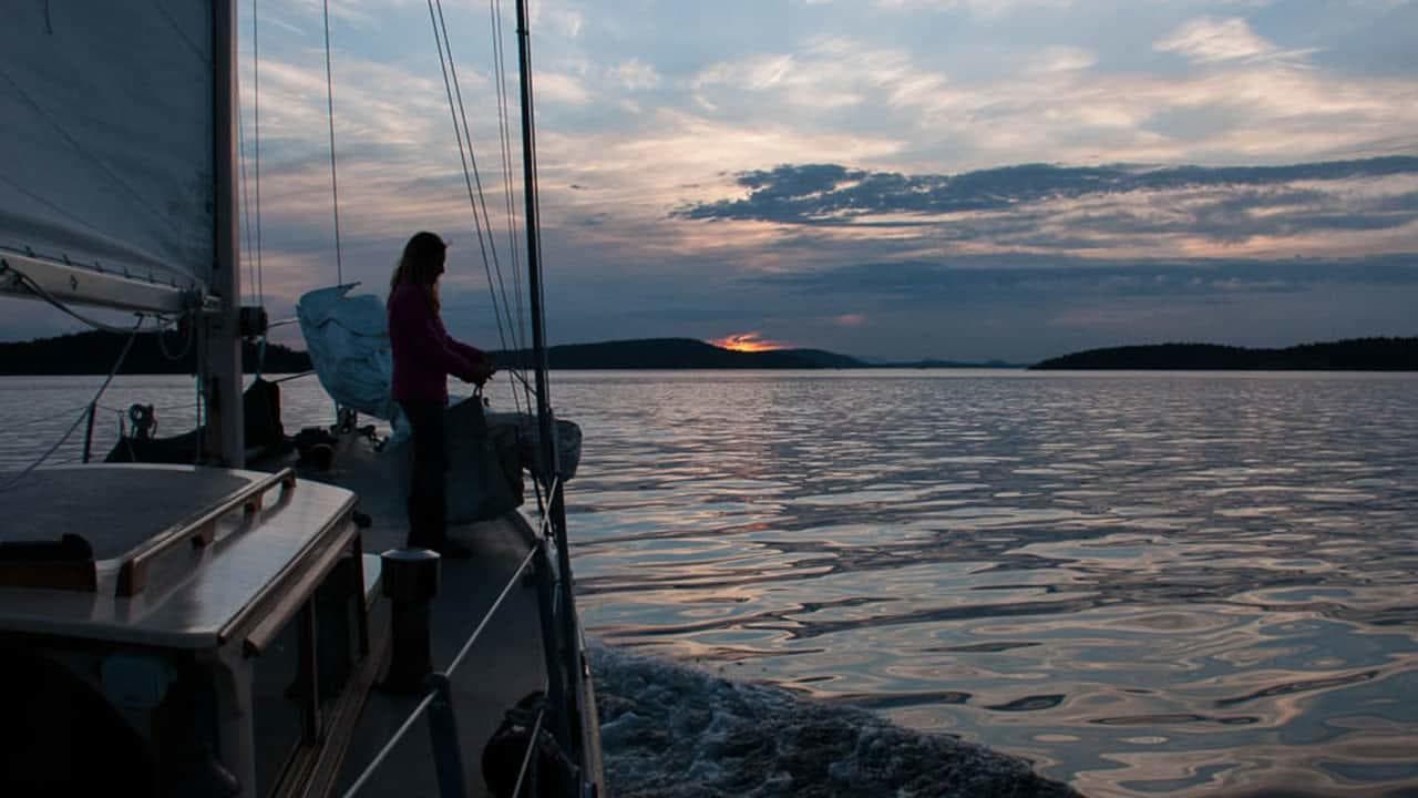 Sailboat cruising at sunset over calm coastal waters