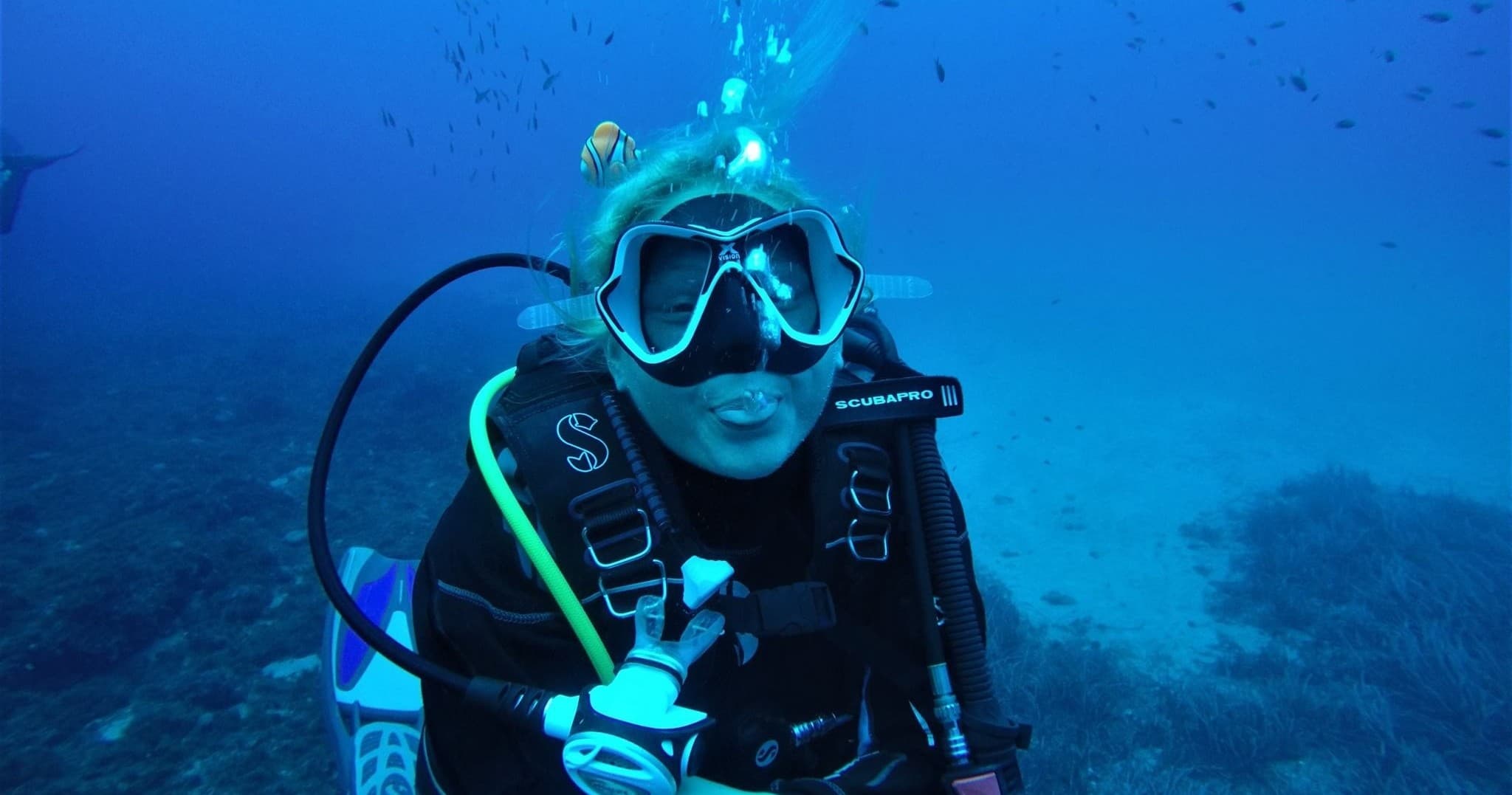 Scuba diver smiling underwater with clear blue ocean backdrop