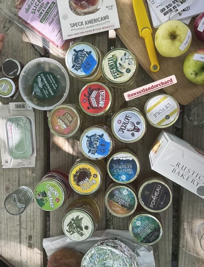 Artisanal preserves and cheese display on picnic table at orchard
