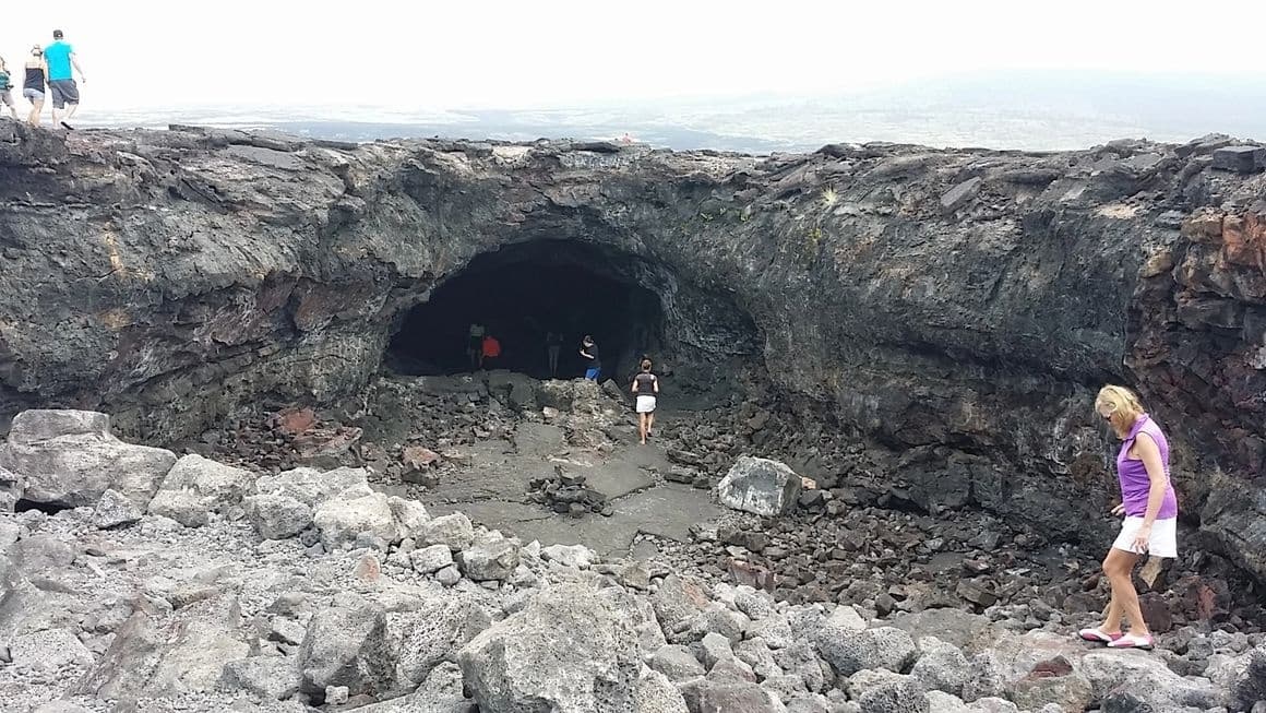 Visitors exploring coastal lava tube cave on rugged shoreline