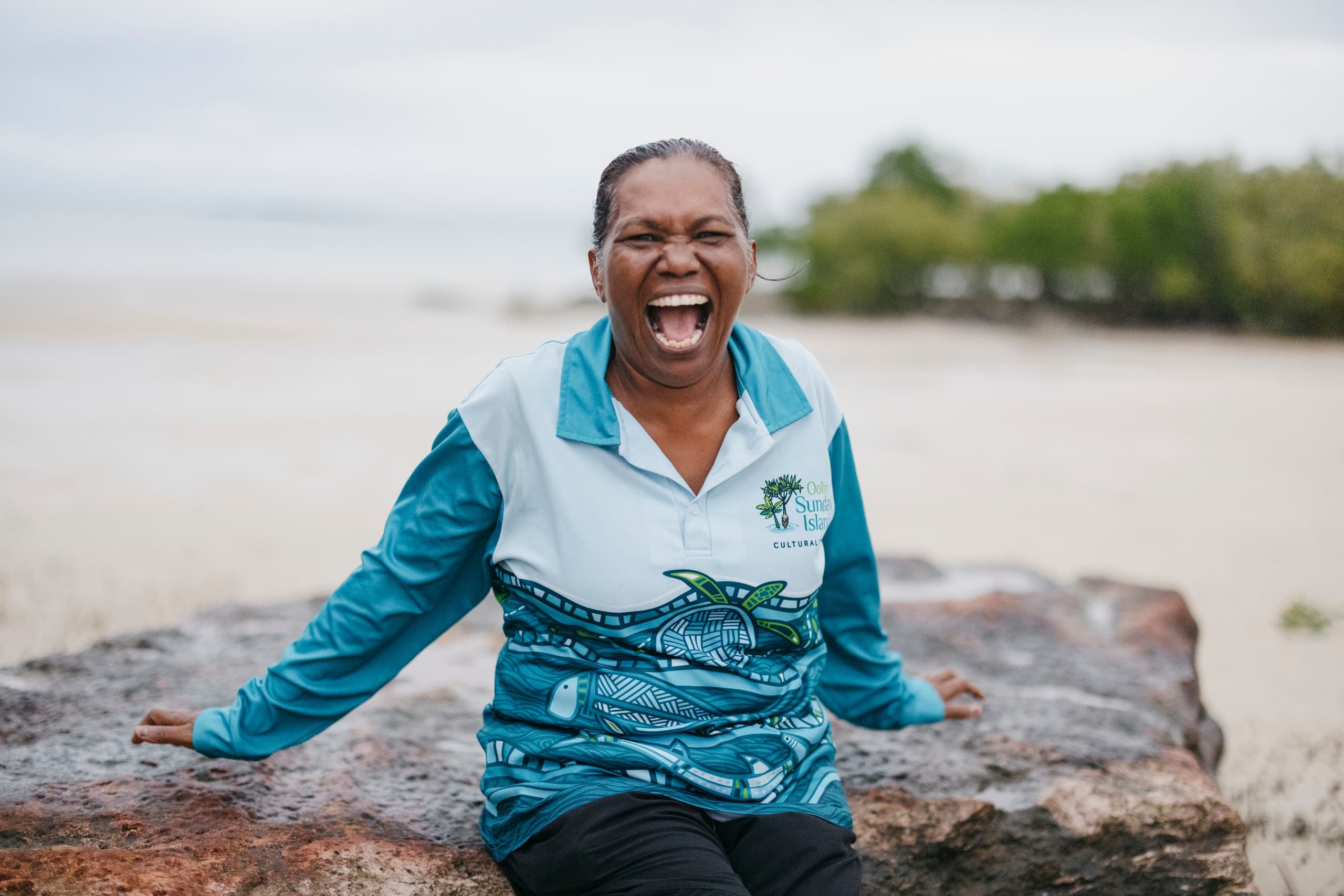 Tour guide laughing on tropical island beach during coastal tour
