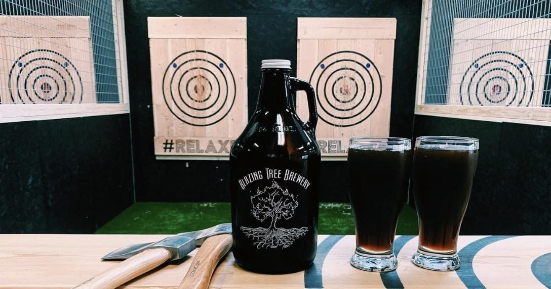 Craft beer and glasses on table with axe throwing targets behind
