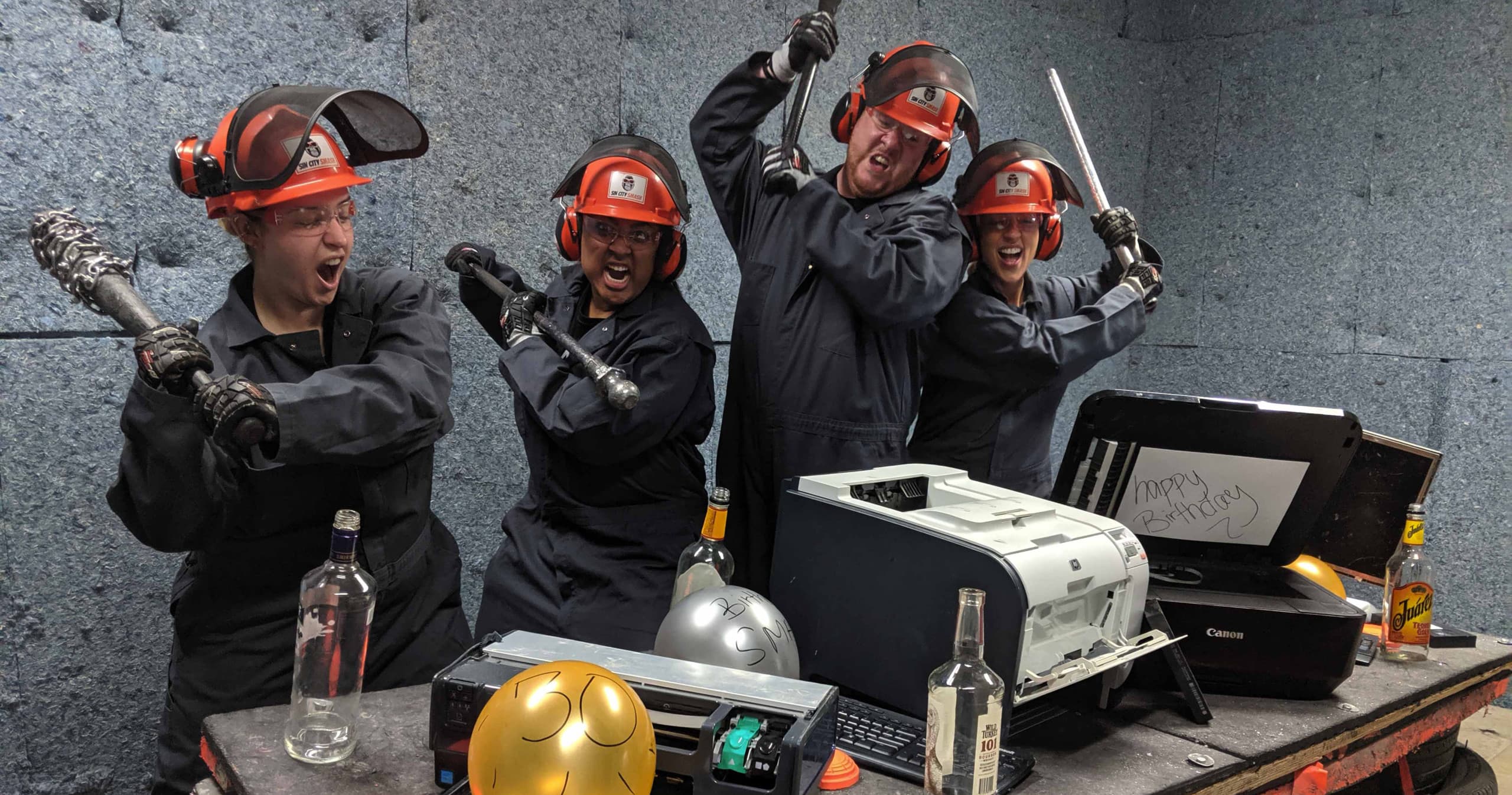 Team posing with smashed items in covered indoor smash studio