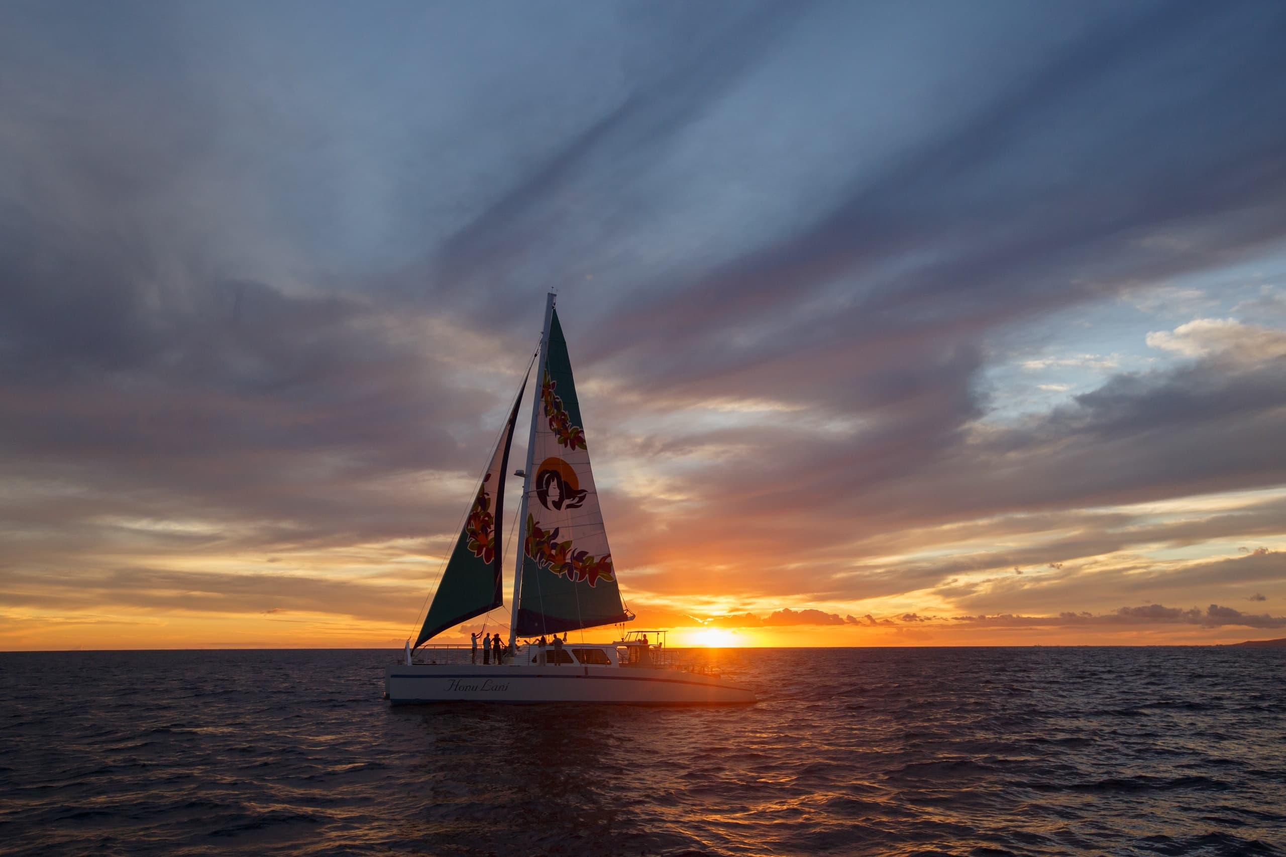 Sailboat at sunset on open ocean with dramatic sky