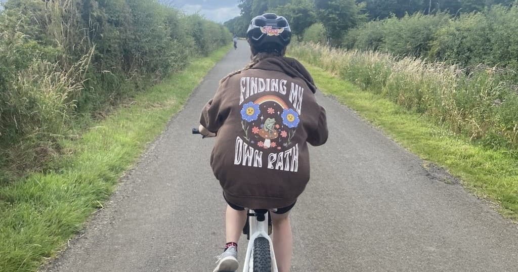 Cyclist pedaling along a quiet country road through fields