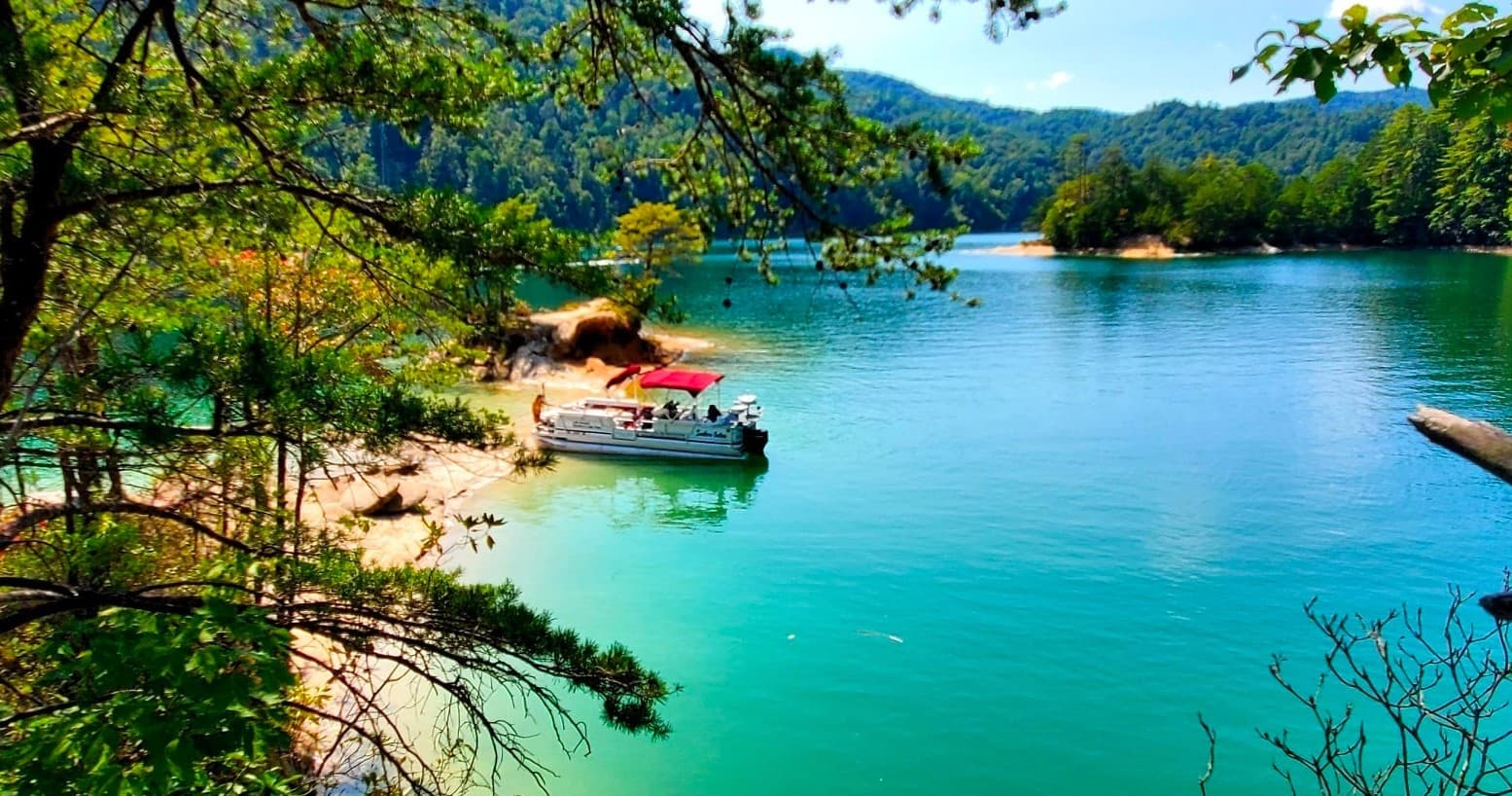 Scenic turquoise lake with anchored boat and pine shoreline