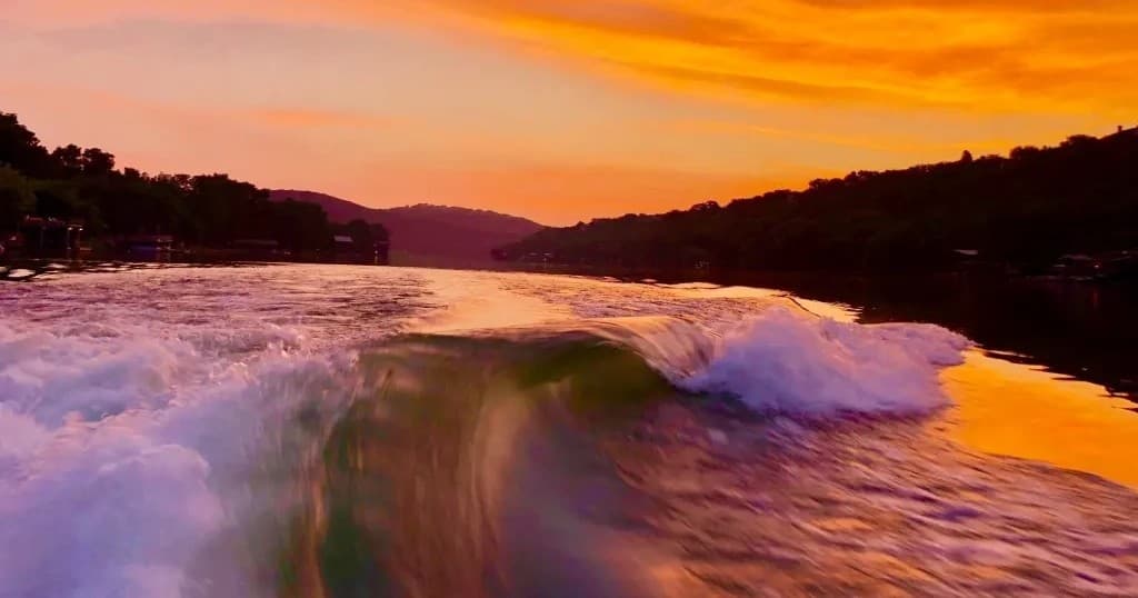 Speedboat wake cutting through lake at sunset with vivid colors