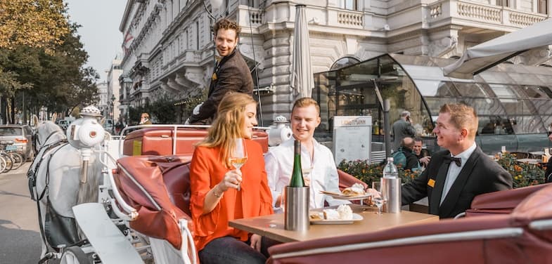 Friends dining in a horse-drawn carriage along city avenue