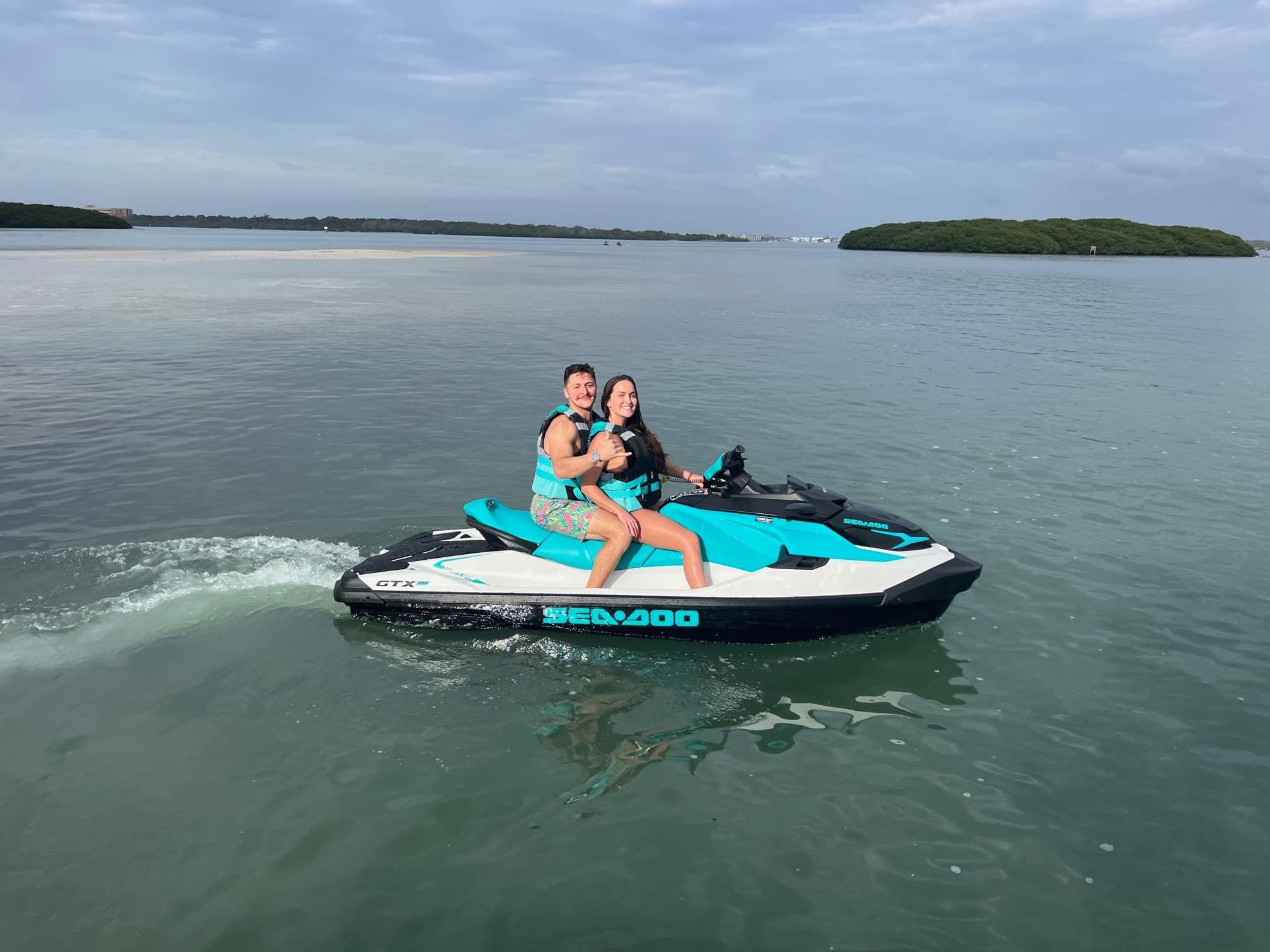 Two people on a Sea-Doo jet ski in coastal mangrove waters