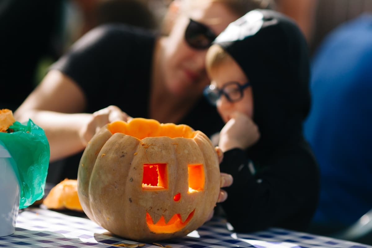 Family pumpkin carving activity outdoors at seasonal market