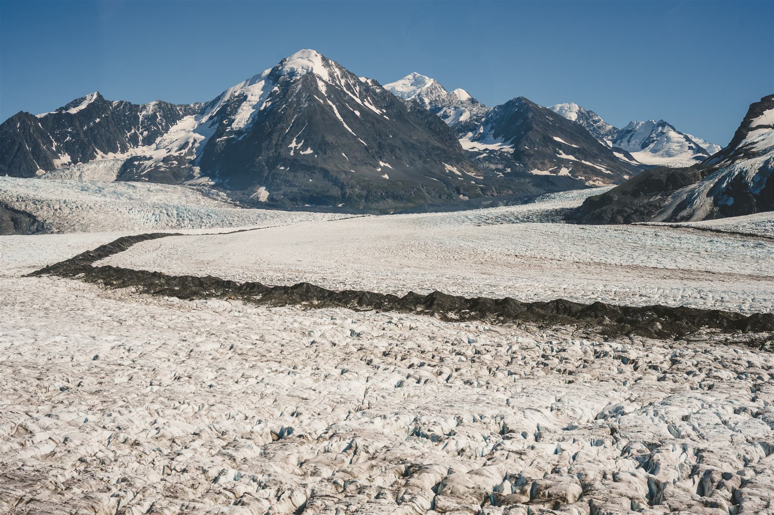 Vast glacier field with rocky moraine and distant peaks