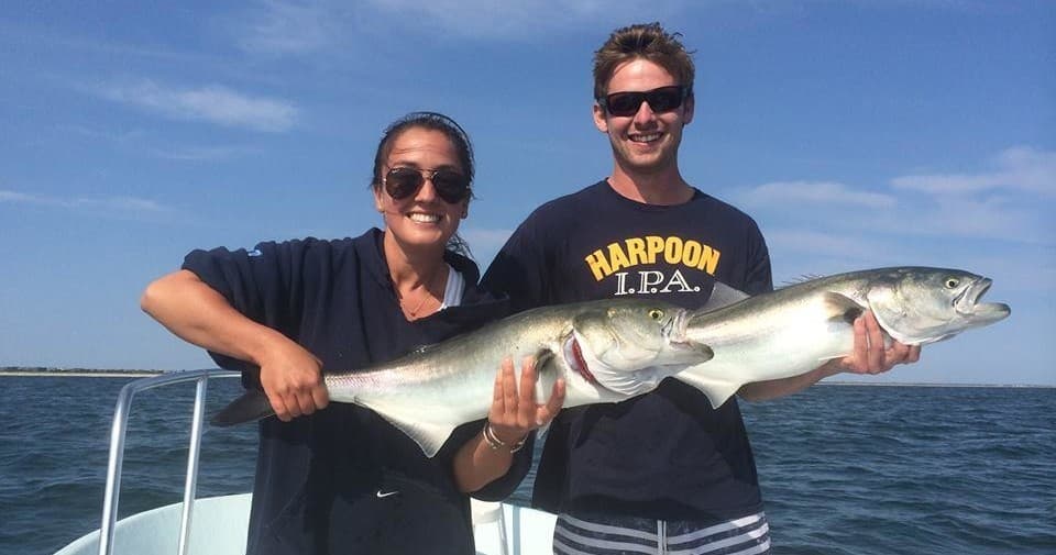 Anglers holding large striped bass on open ocean charter