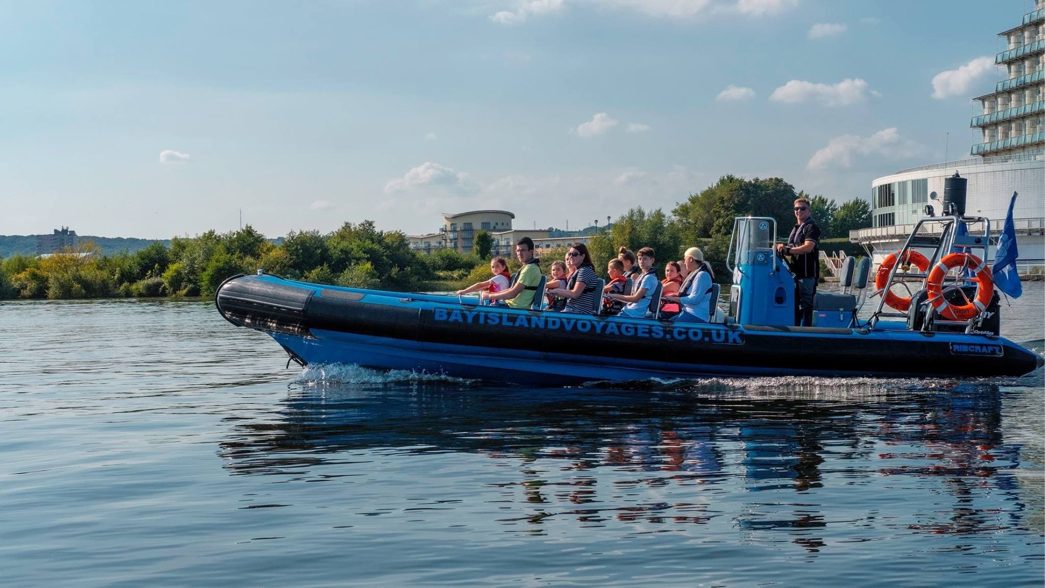 Rigid inflatable boat tour with passengers near waterfront harbor