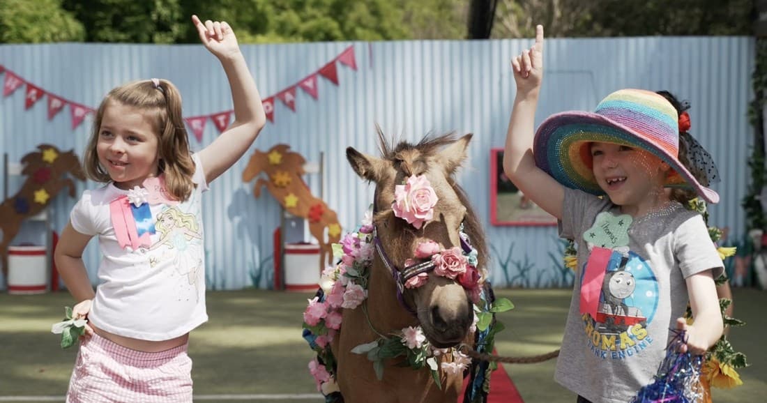 Children celebrating with decorated pony at outdoor party