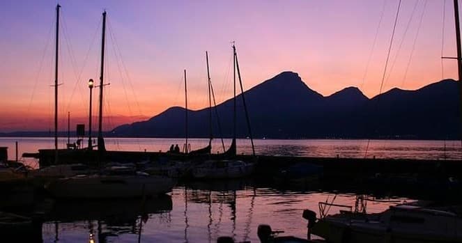 Sailboats moored at sunset with mountain silhouette, lakeside view