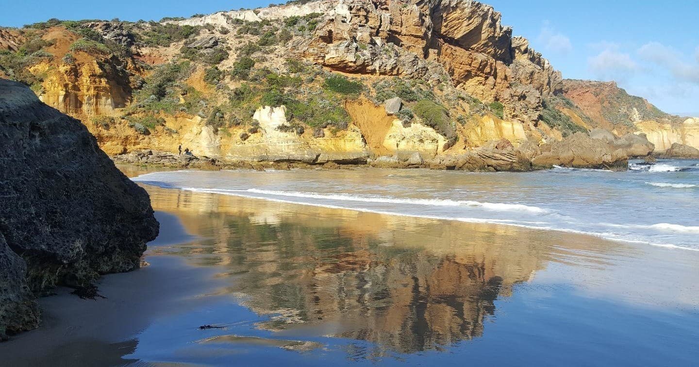 Rocky shoreline reflecting cliffs and tidal pools at coast