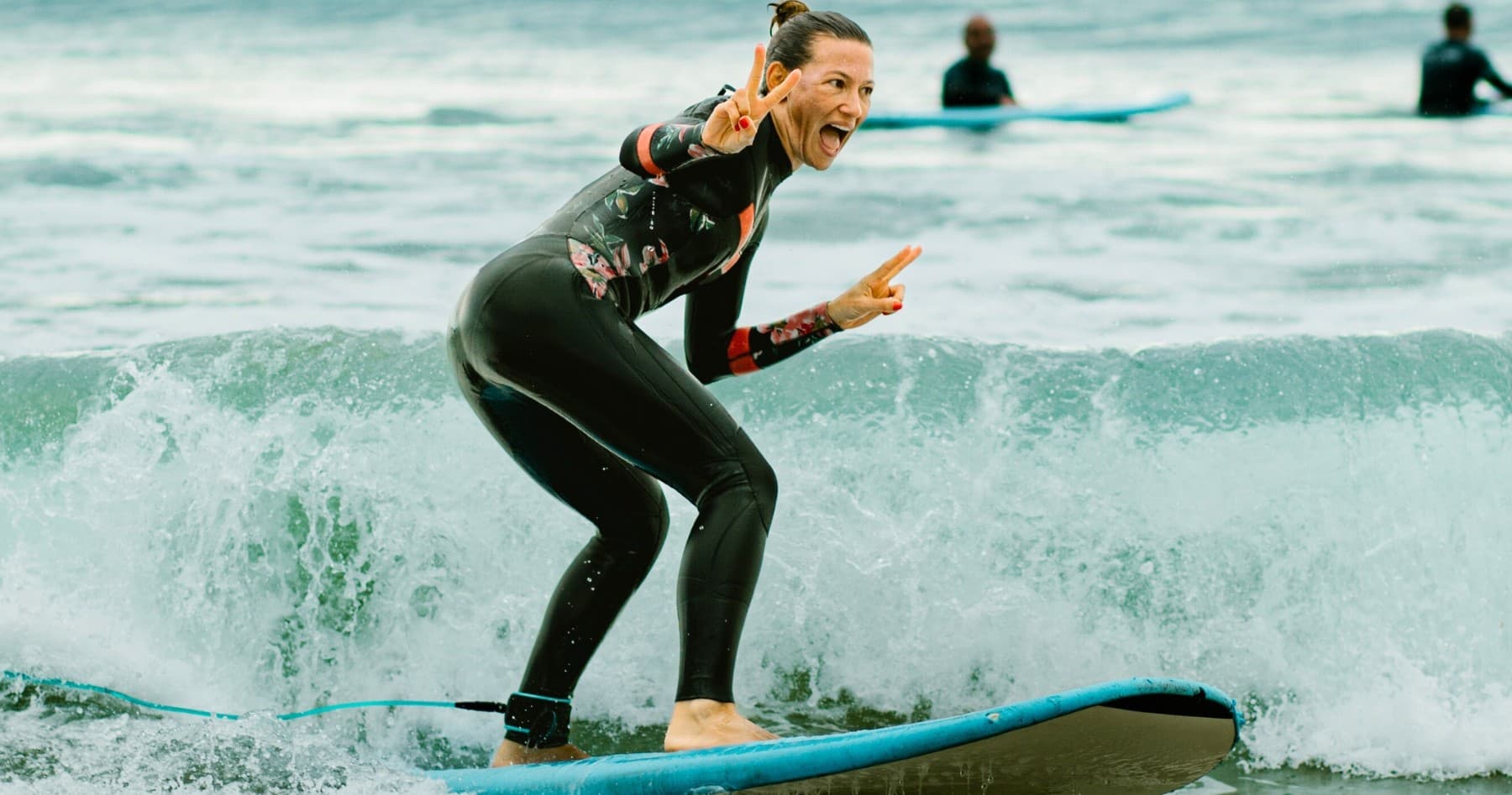 Surfer riding breaking ocean wave on blue surfboard at sea