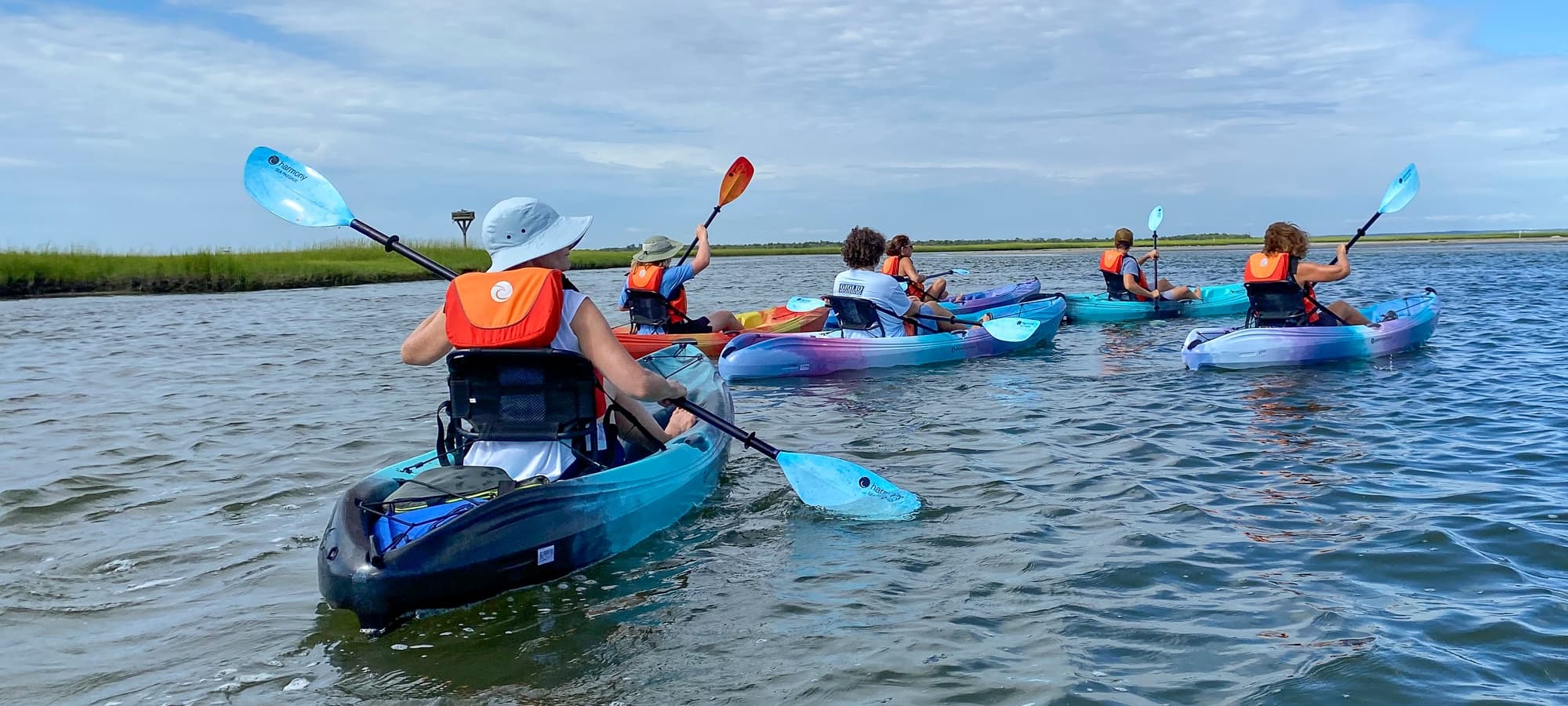 Group kayaking on calm coastal waters with scenic horizon