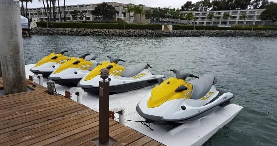 Three jet skis docked at marina ready for ocean rentals