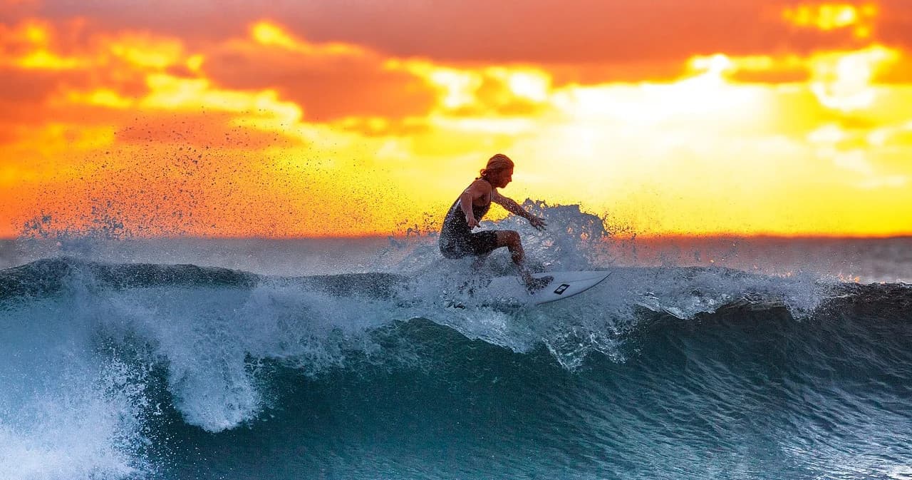 Surfer carving a wave at sunset on Hawaiian coastline
