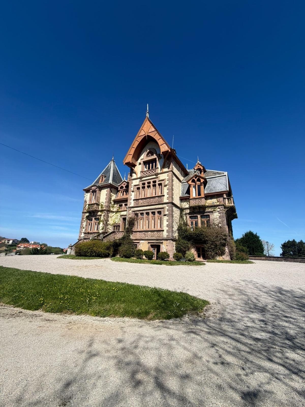 Victorian seaside mansion on manicured grounds under blue sky