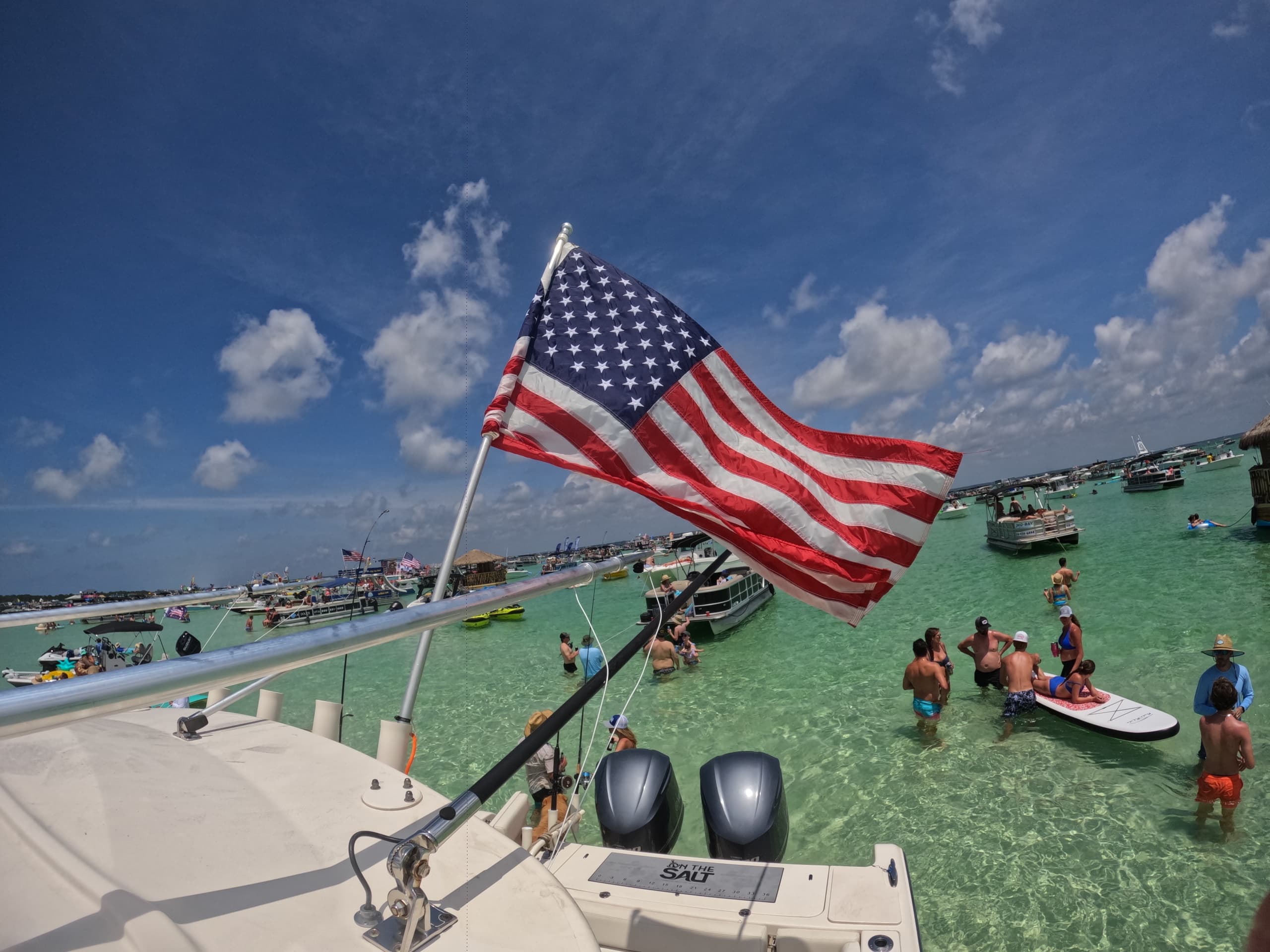 American flag over sandbar party and paddleboards in turquoise water
