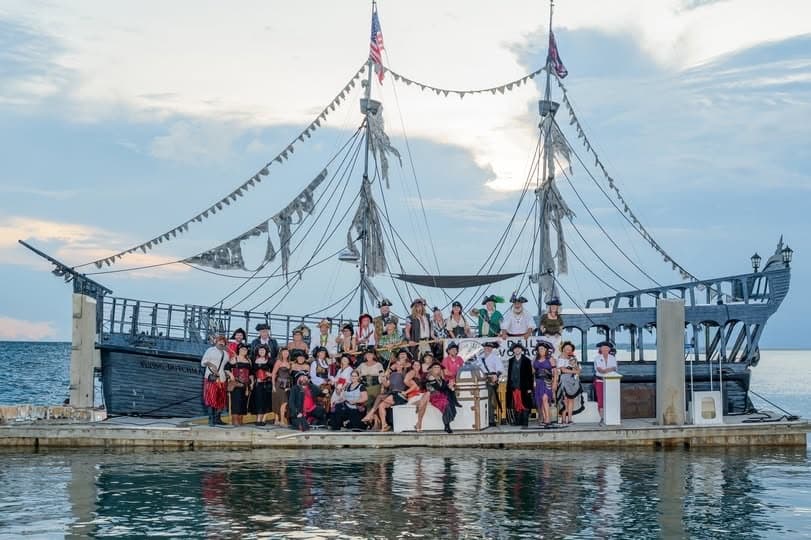 Large group aboard pirate ship docked near coastal harbor