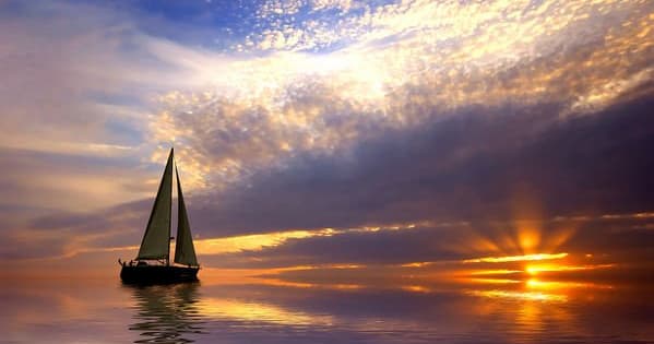 Sailboat sailing at sunset over calm open ocean horizon