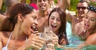 Friends laughing and drinking in outdoor resort pool party