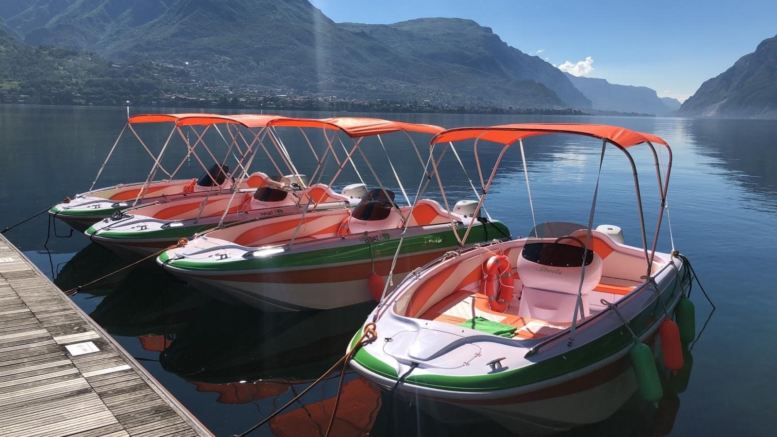 Colorful rental boats docked on misty lake with mountain backdrop
