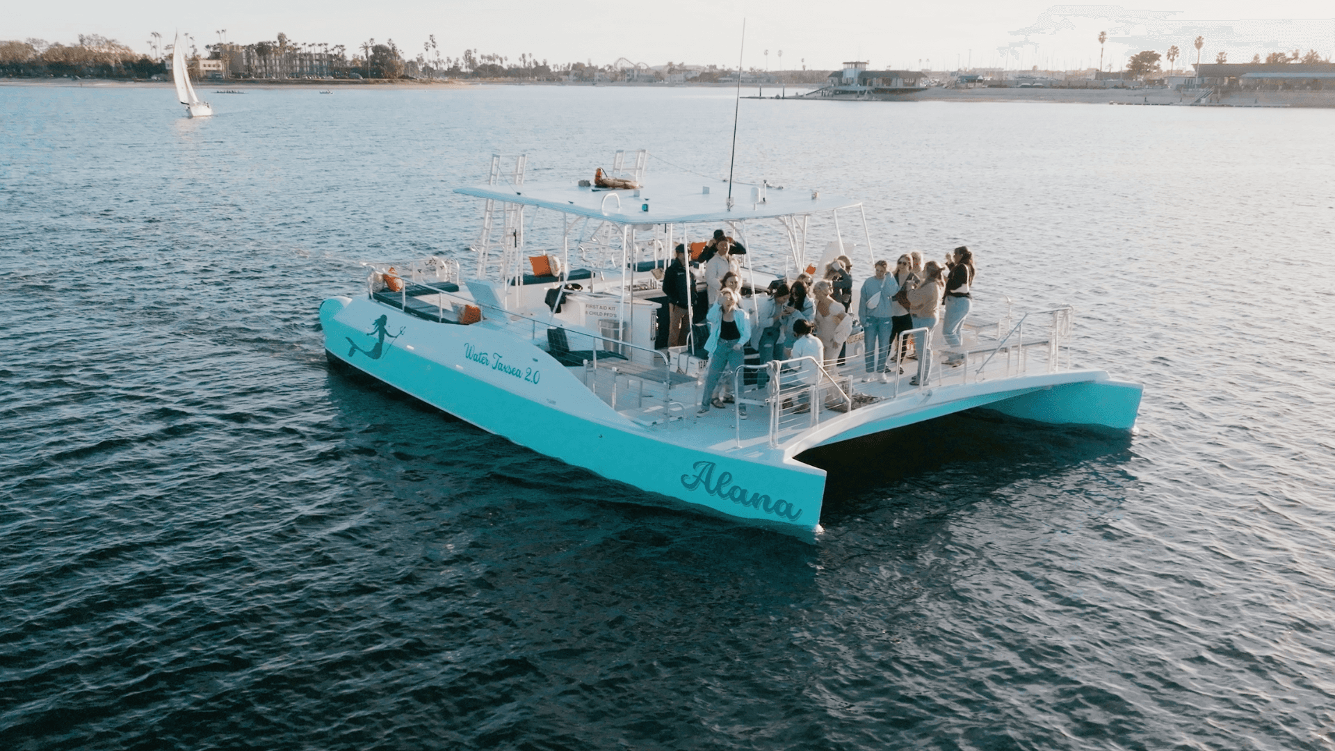 Side view of turquoise tour boat gliding across bay at dusk