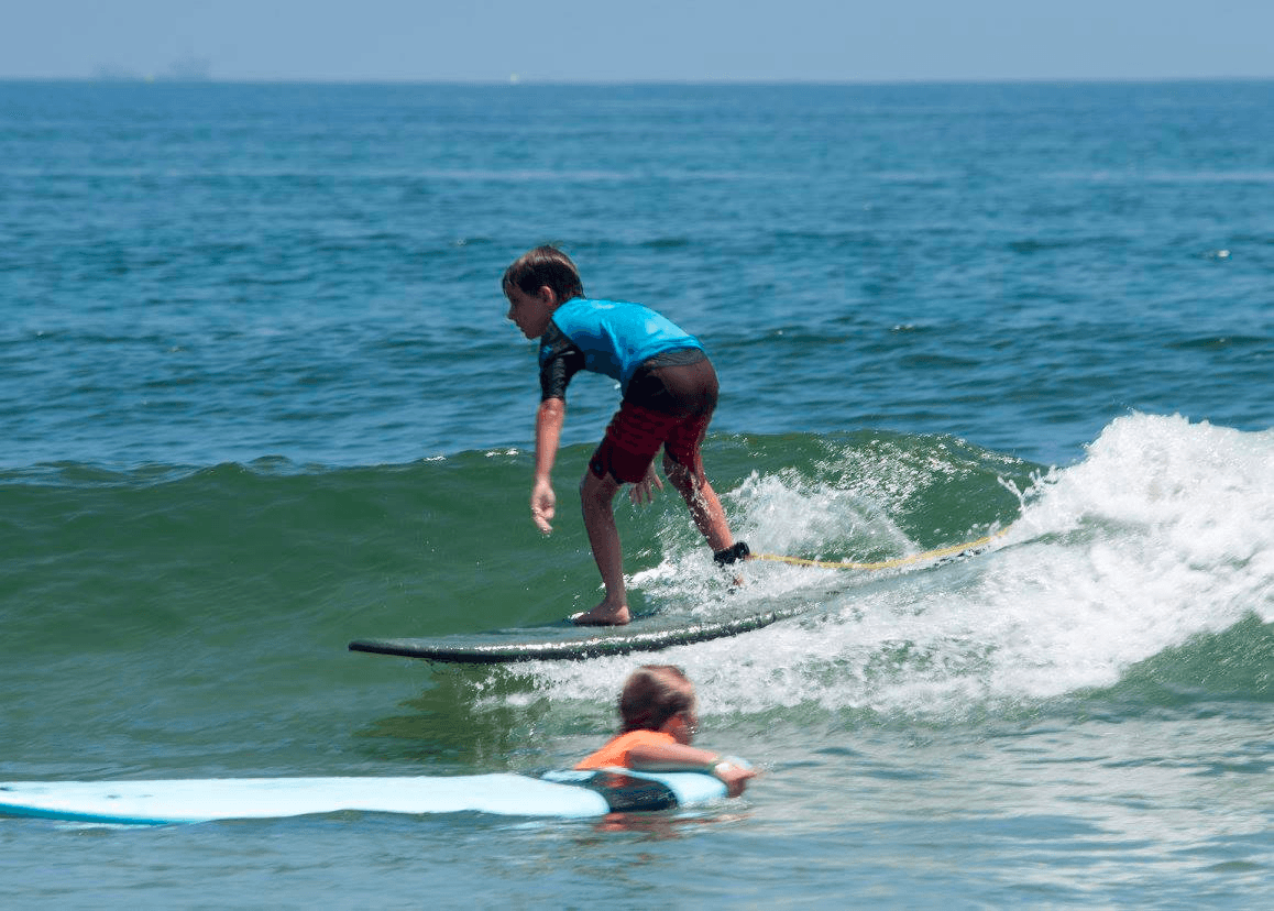 Longboard surfer riding small wave with paddleboarder nearby