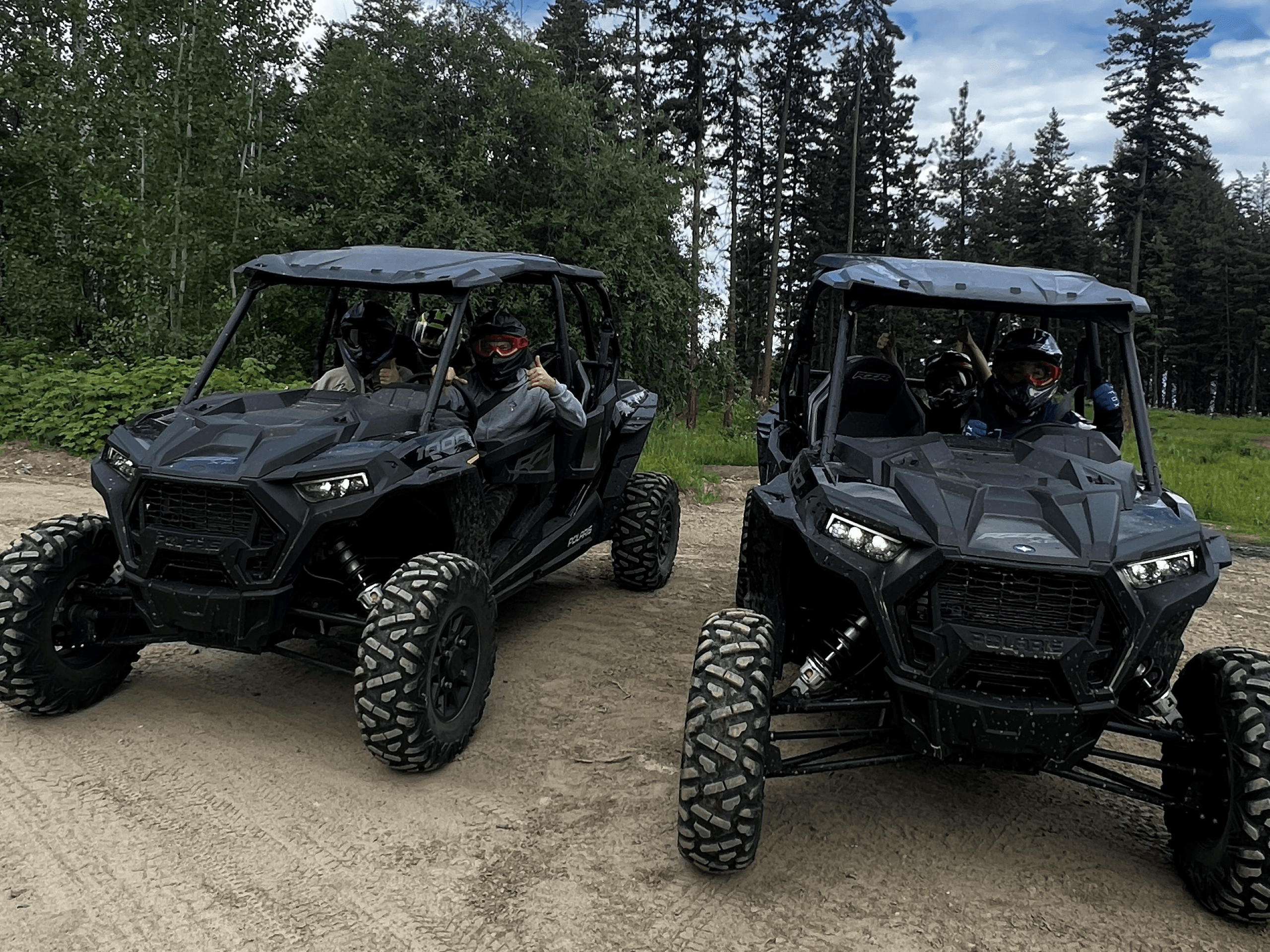 Two black UTV side-by-side vehicles on forest dirt road