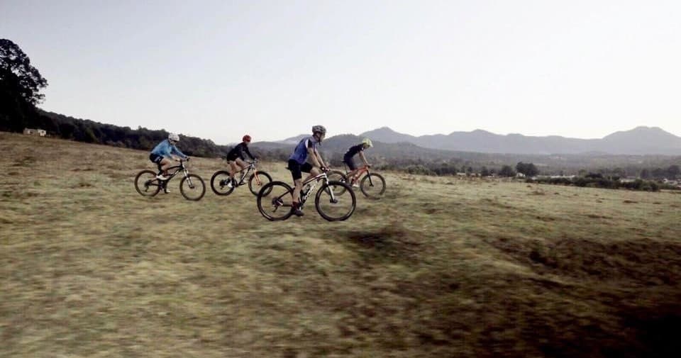 Mountain bikers riding across open plain at dawn in highlands