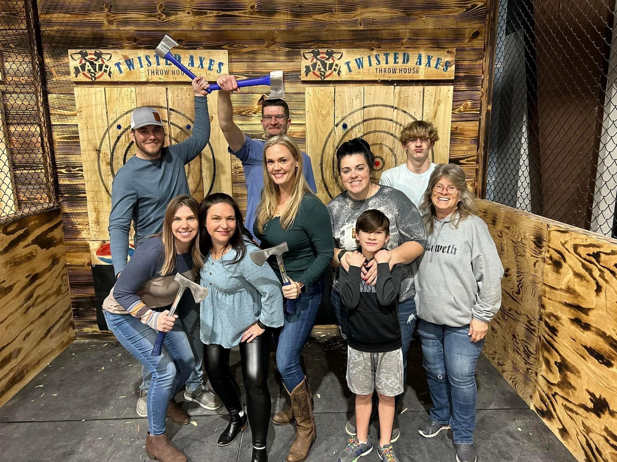 Group posing inside axe throwing lane at mobile event