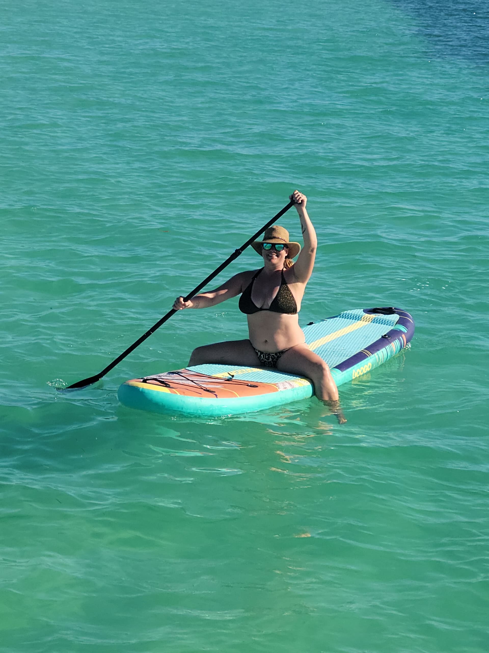 Standup paddleboarder paddling on clear turquoise coastal waters