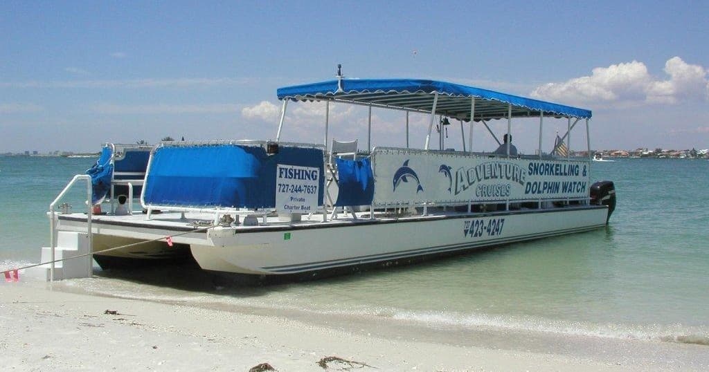 Covered tour boat beached on tropical shore for shelling excursions