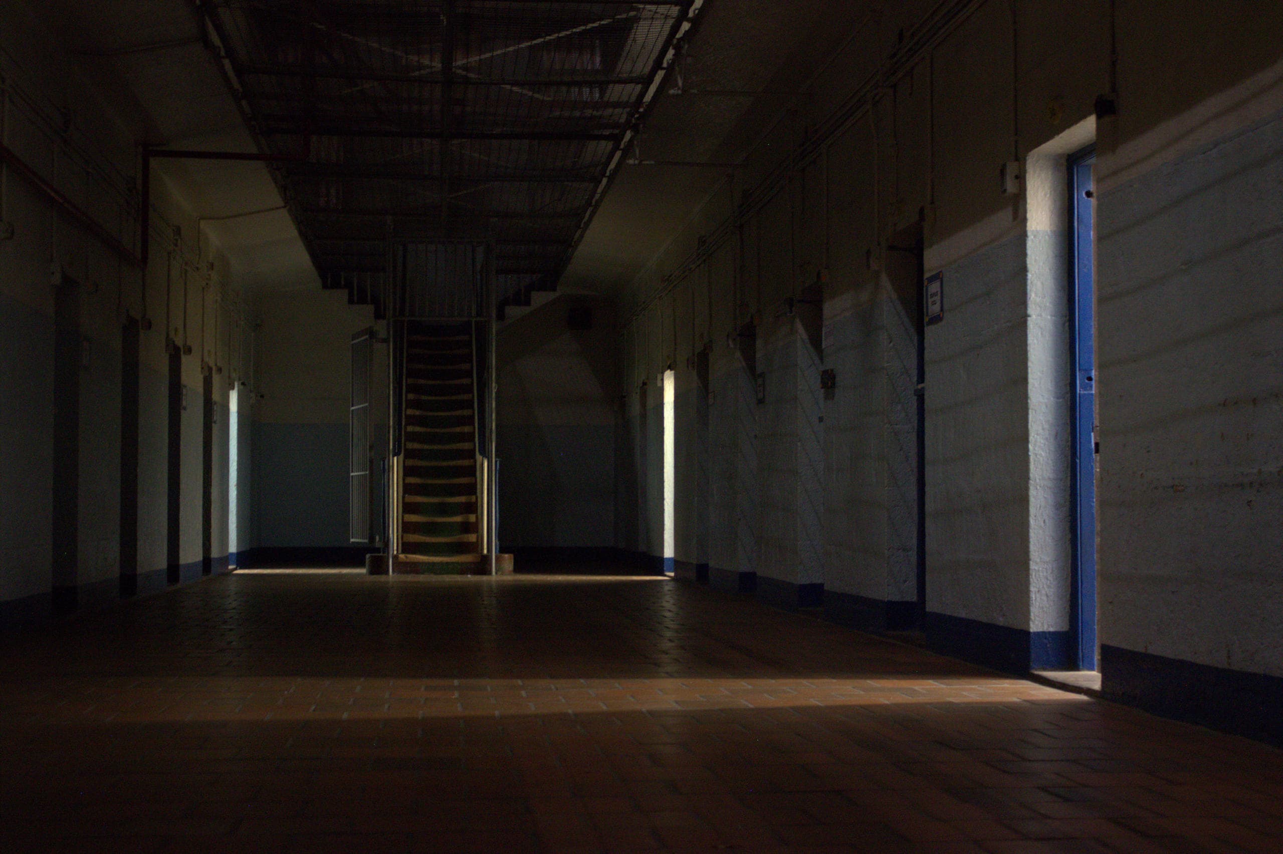 Dim gaol corridor interior with central stair, guided tour preview