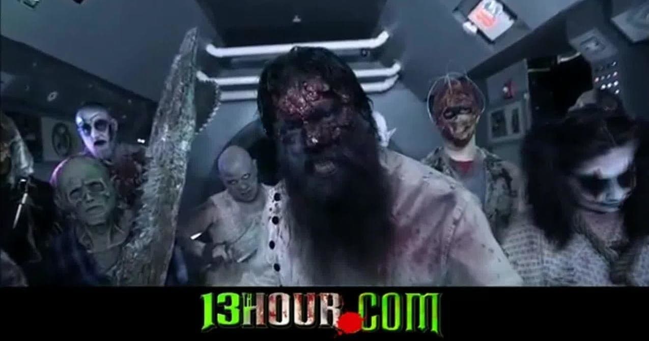 Crowd of costumed zombies in dim haunted attraction hallway