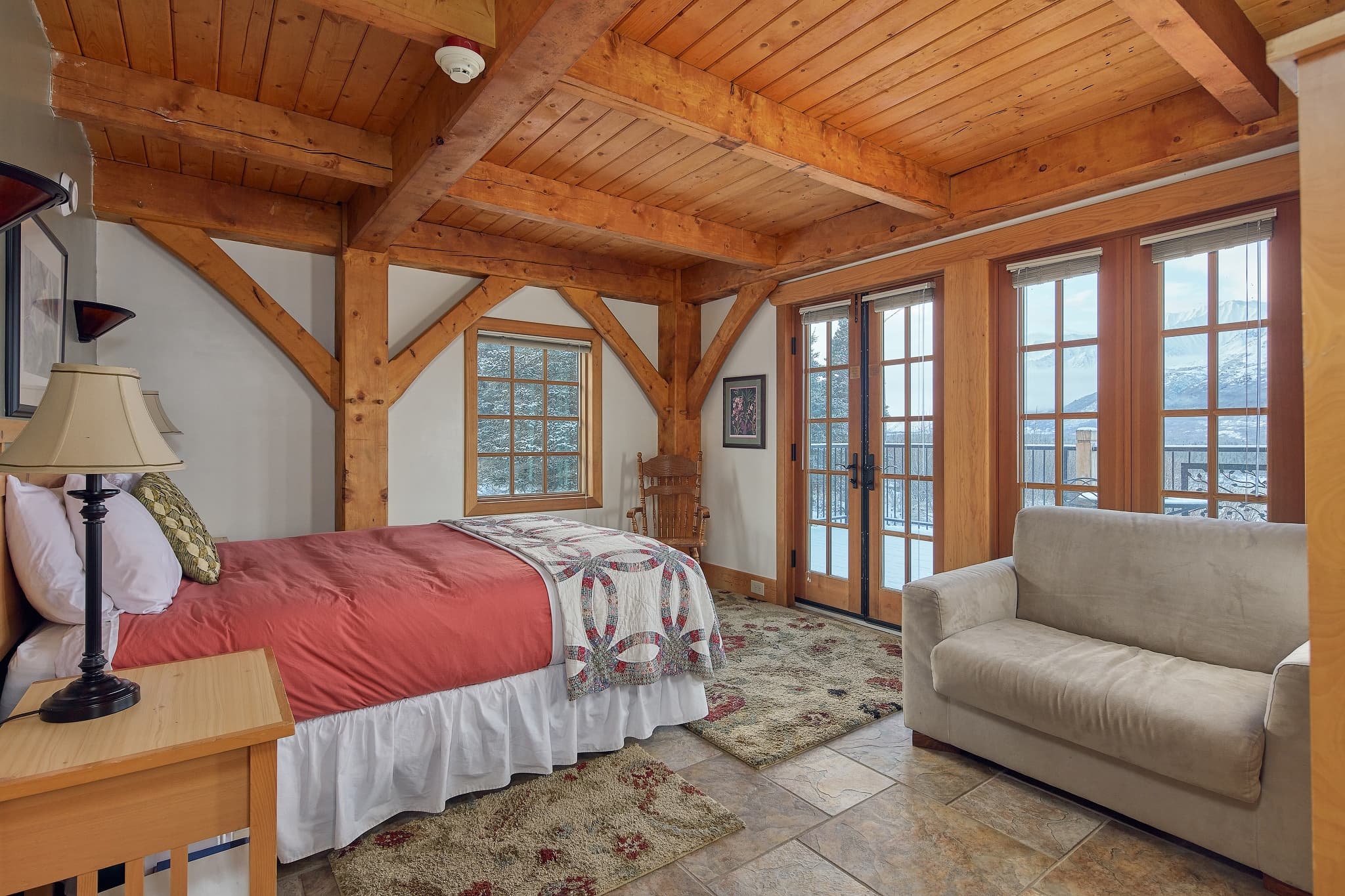 Rustic timber lodge bedroom with cozy seating and mountain views