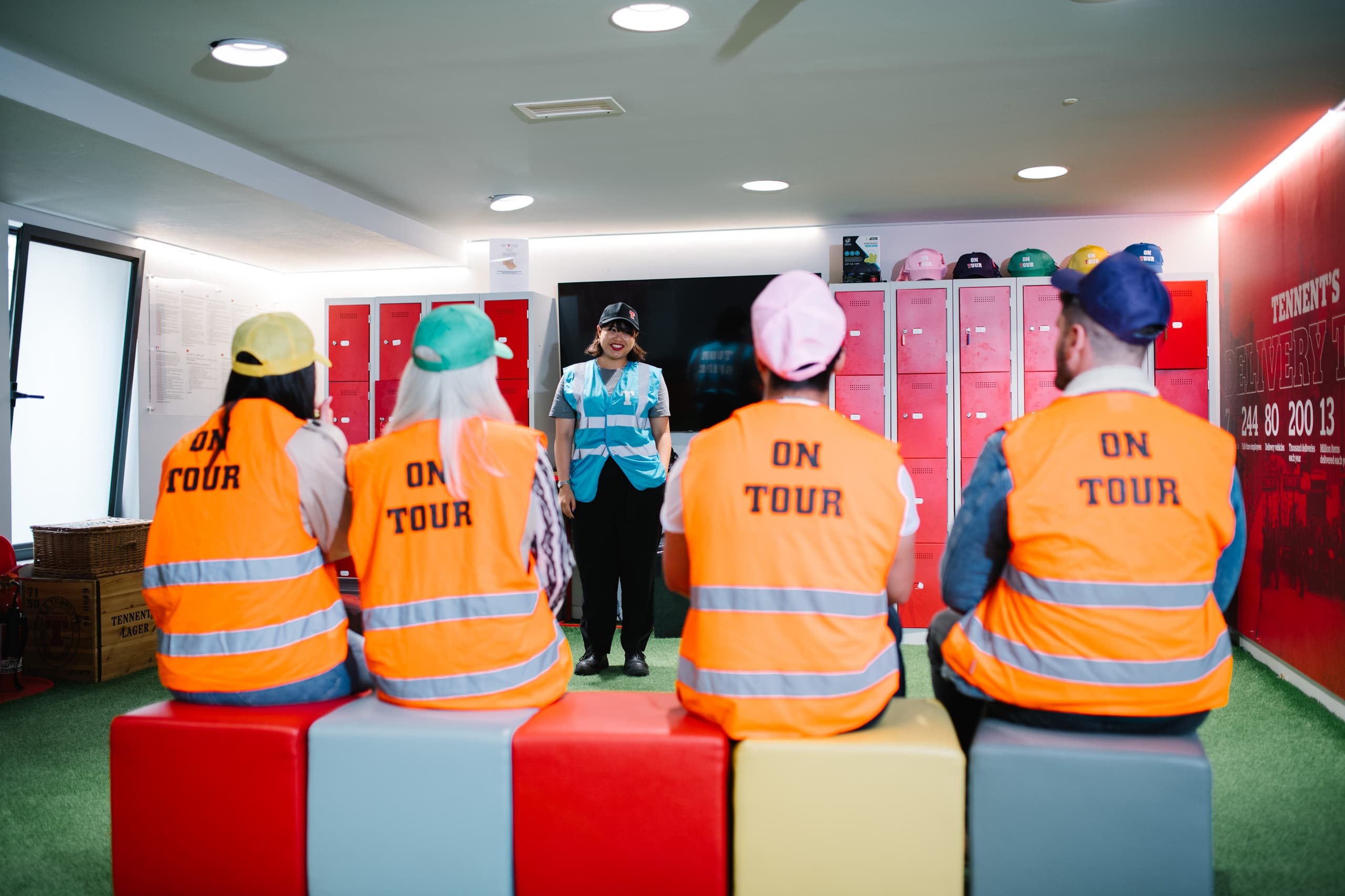 Tour group wearing high-vis vests seated in locker room tour