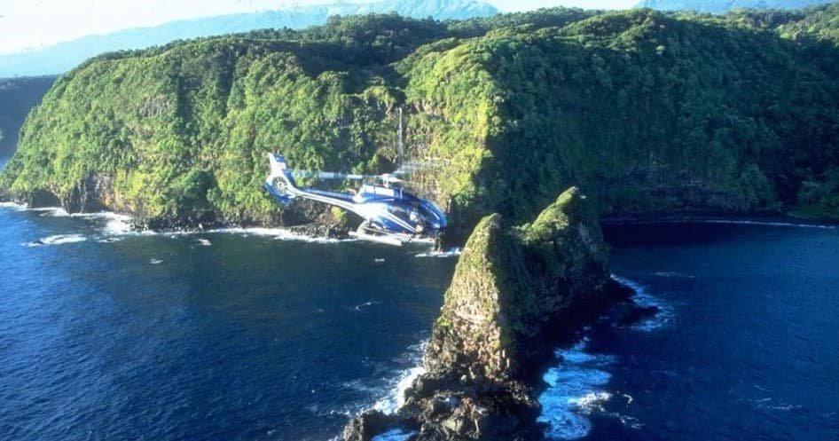 Helicopter flying over steaming volcanic crater rim in Hawaii